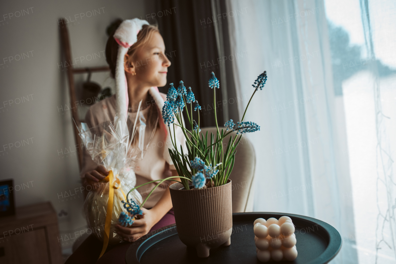 Girl with bunny ear headband holding an Easter egg gift. Springtime holiday celebration.