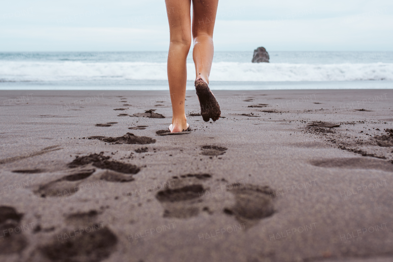 Rear view of kid running across the beach into sea. Concept of family beach summer vacation with kids.