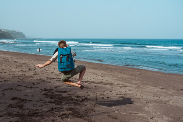 Boy is excited to be on a family vacation, jumping on the beach.