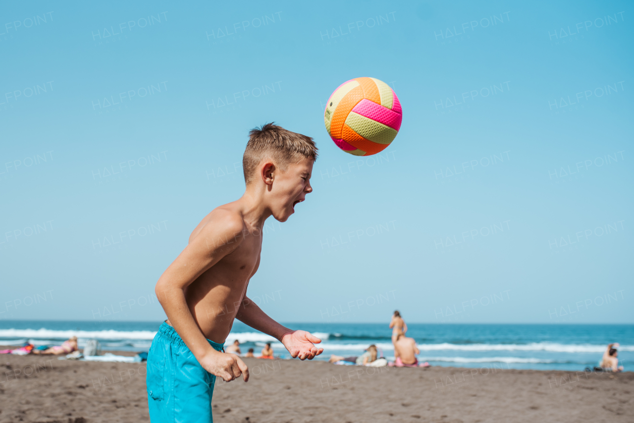 Young boy playing soccer on a sandy beach, enjoying a family vacation.