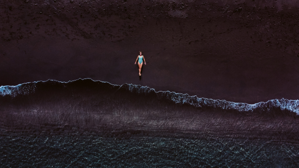 Aerial view of woman lying on a sandy beach near the water.