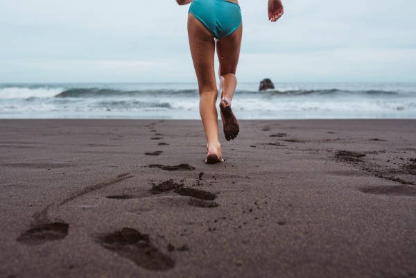 Rear view of kid running across the beach into sea. Concept of family beach summer vacation with kids.