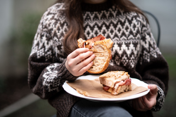 Girl enjoying a homemade baked sandwich with bacon, holding plate.