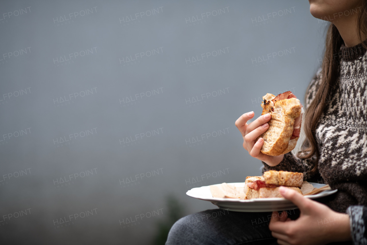 Side view of girl enjoying a homemade baked sandwich with bacon, holding plate.