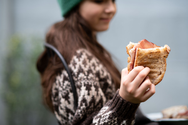 Girl enjoying a homemade baked sandwich with bacon, holding plate.