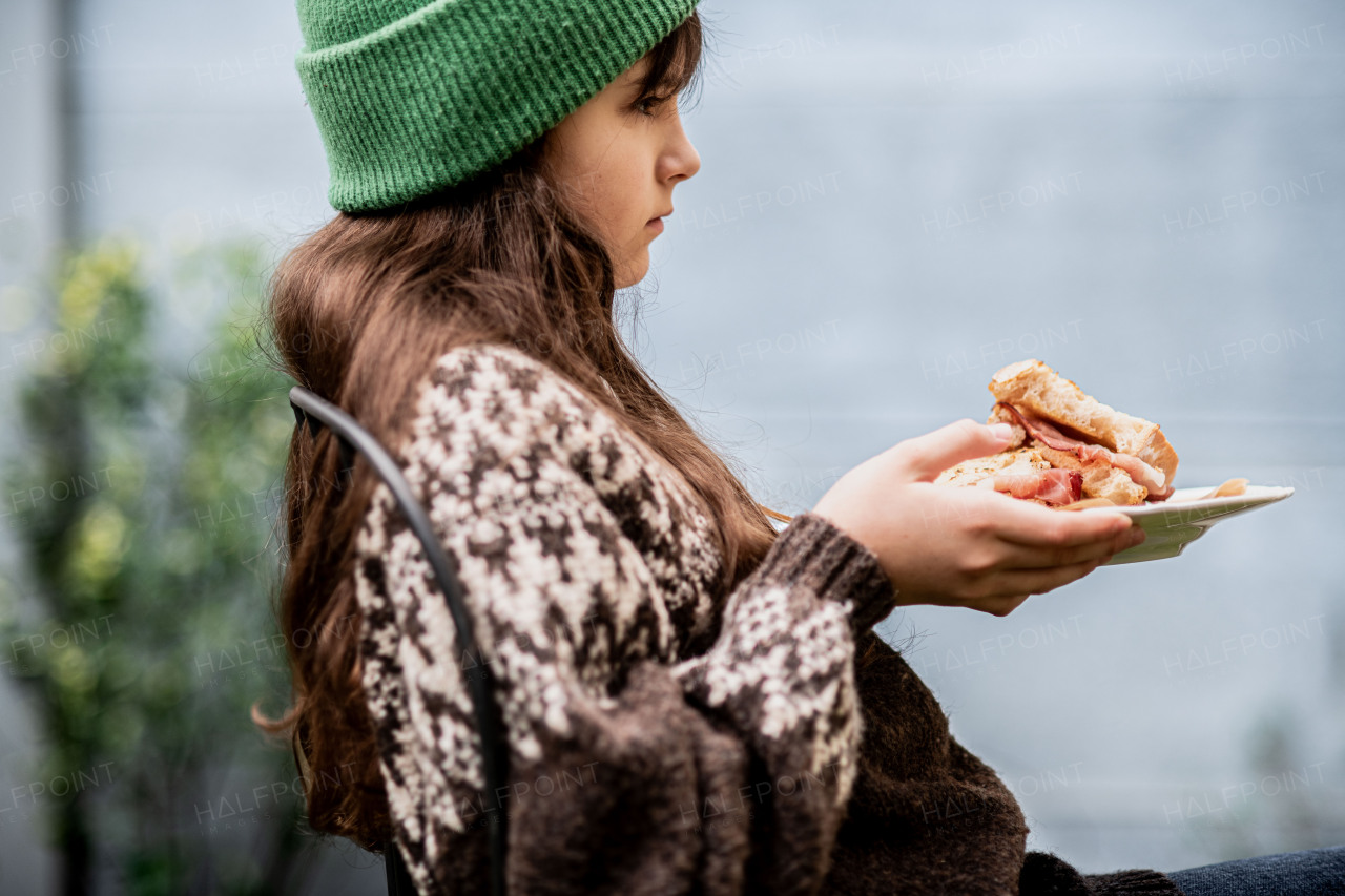 Girl enjoying a homemade baked sandwich with bacon, holding plate.