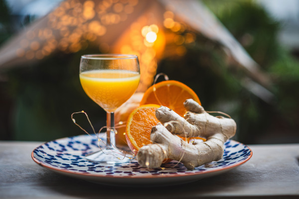 Powerful ginger shot with fresh oranges and ginger root on a rustic table