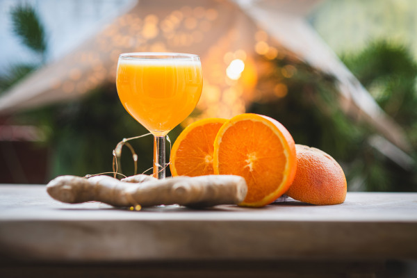 Powerful ginger shot with fresh oranges and ginger root on a rustic table