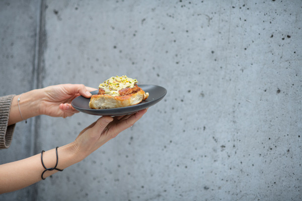 Close up of hands holding plate with pistachio cinnamon bun.