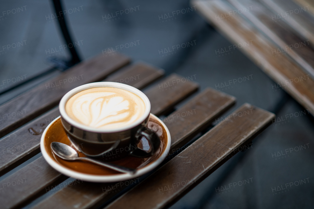 Cup of cappuccino with latte art on a rustic wooden table in a cozy cafe setting.