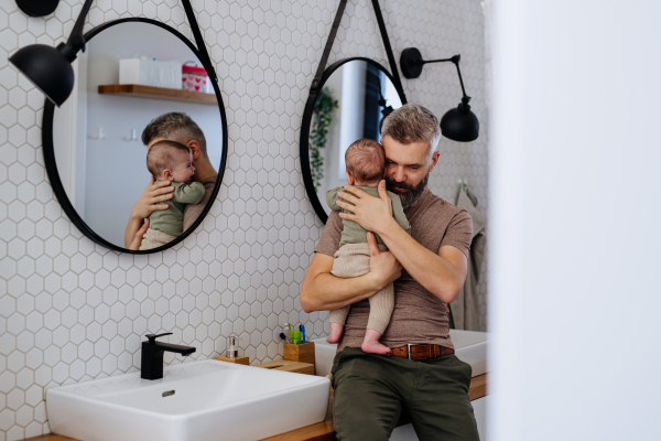 Father comforting his crying baby son, holding him in arms.