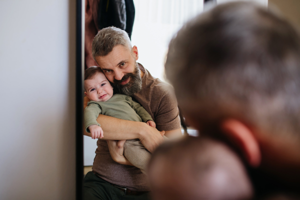 Father comforting his crying baby son, holding him in arms.