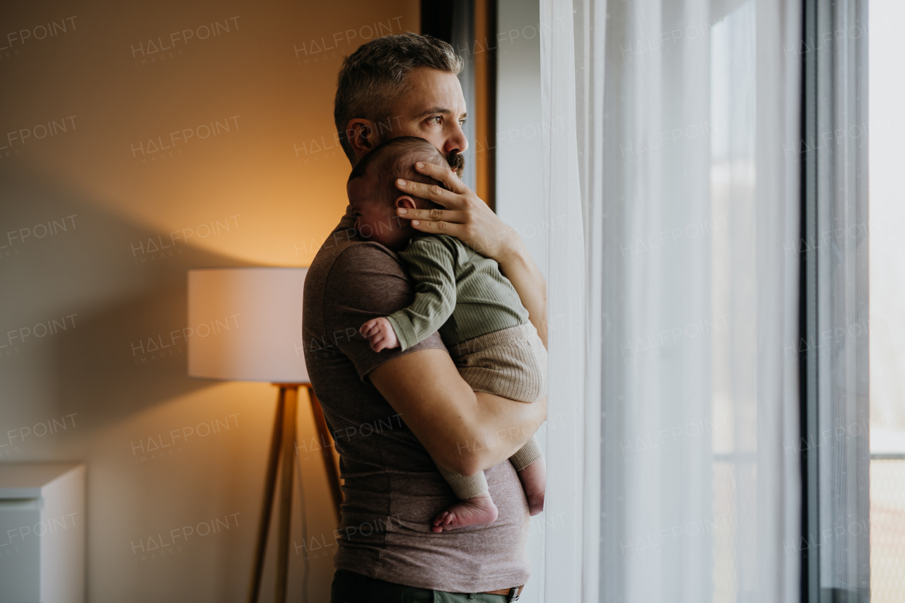 Father comforting his crying baby son, holding him in arms.