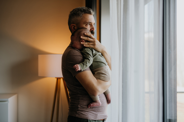 Father comforting his crying baby son, holding him in arms.