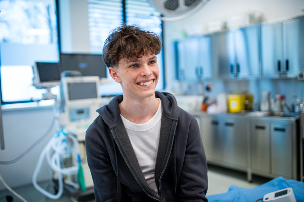 Teenage boy smiling during supportive medical consultation after receiving positive health news.