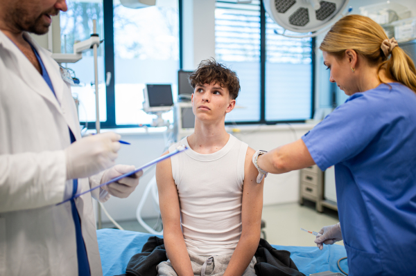 Teenage boy receiving vaccination during routine health checkup at hospital