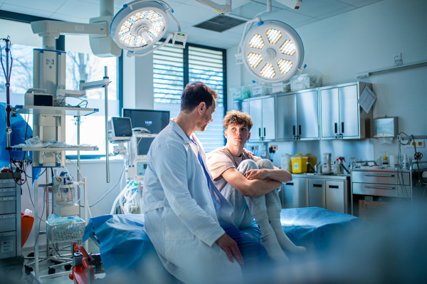Teenager confiding in doctor about personal and health problems. Mental health evaluation for depressed teen boy.
