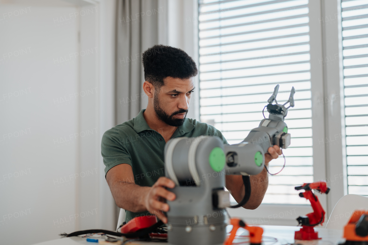 Young engineer building and programming a robotic arm at home. Robotics concept.