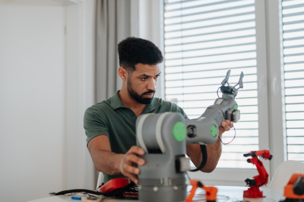 Young engineer building and programming a robotic arm at home. Robotics concept.