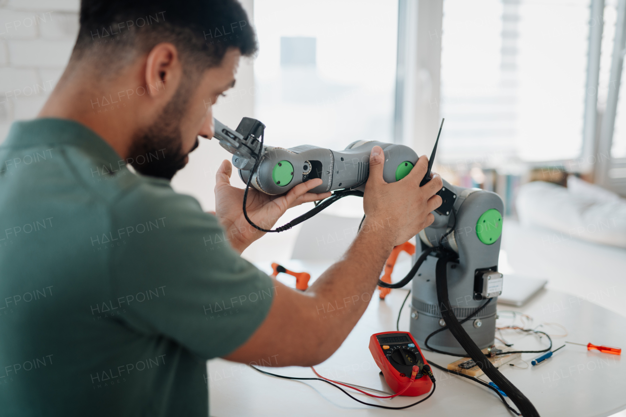 Young engineer building and programming a robotic arm at home. Robotics concept.