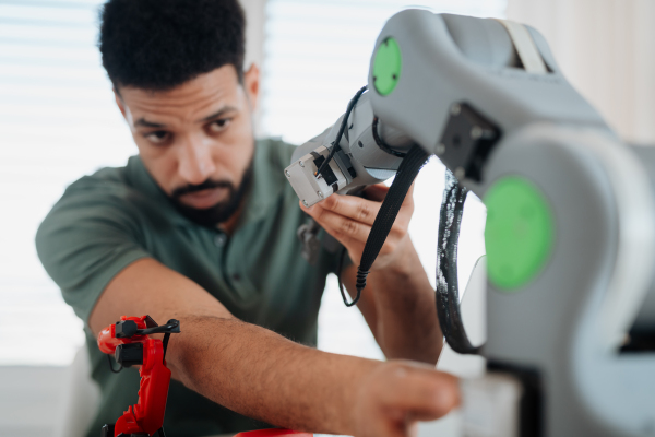 Young innovator developing robotic arm as part of home tech project. Robotics concept.