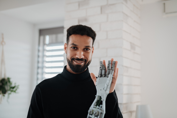 Portrait of young engineer holding robotic arm. Robotics concept.