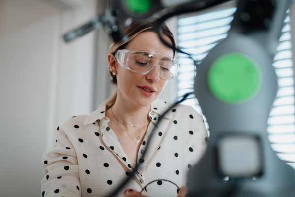 Female engineer building and programming a robotic arm at home. Robotics concept.