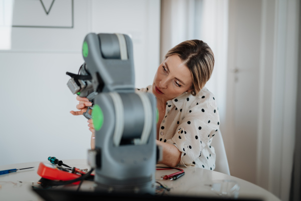 Female engineer building and programming a robotic arm at home. Robotics concept.