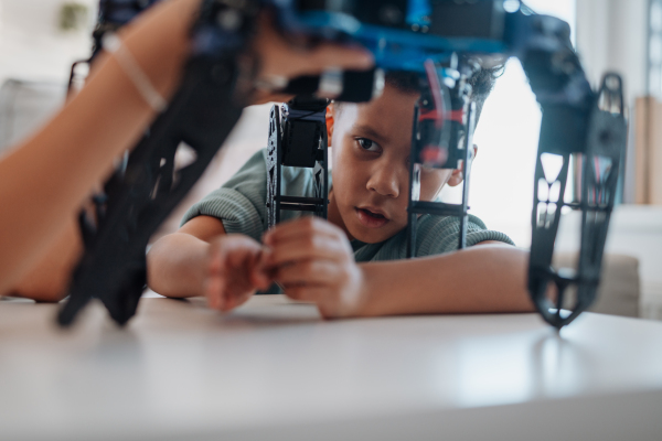 Focused boy building and programming robot car at home as part of STEM learning.