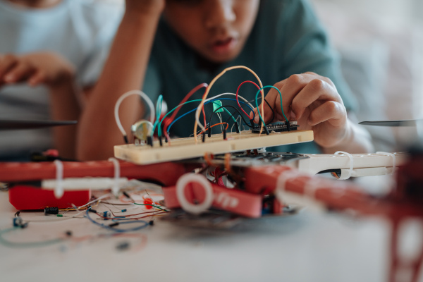 Young schoolboy assembling robotic kit and working with circuit board at home.