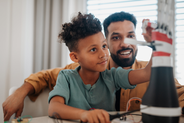 Father teaching son about STEM, robotics, and discussing technology at home.