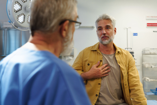 Patient sitting on examination table, describing health problems and symptoms to doctor.