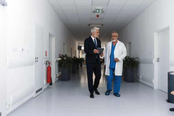 Doctor talking with hospital manager, walking down the hospital hallway.