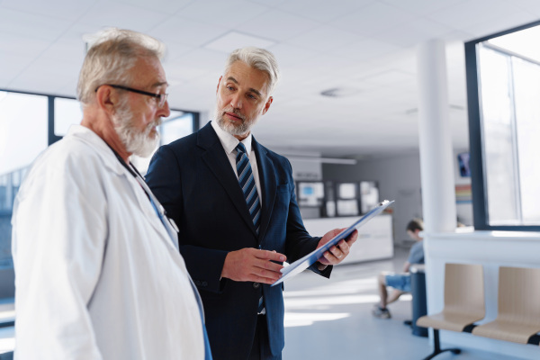 Doctor talking with hospital manager, walking down the hospital hallway.