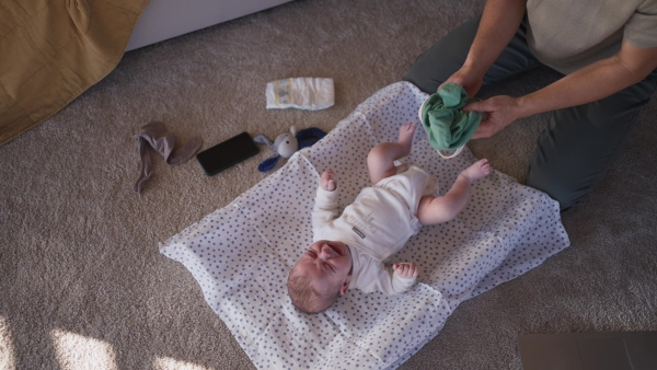 A single father changing diapers of his baby son.