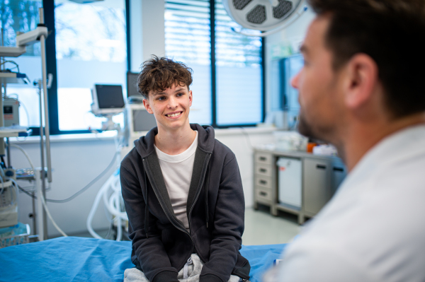 Teenage boy smiling during supportive medical consultation after receiving positive health news.