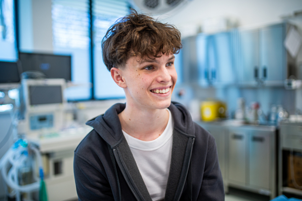 Teenage boy smiling during supportive medical consultation after receiving positive health news.