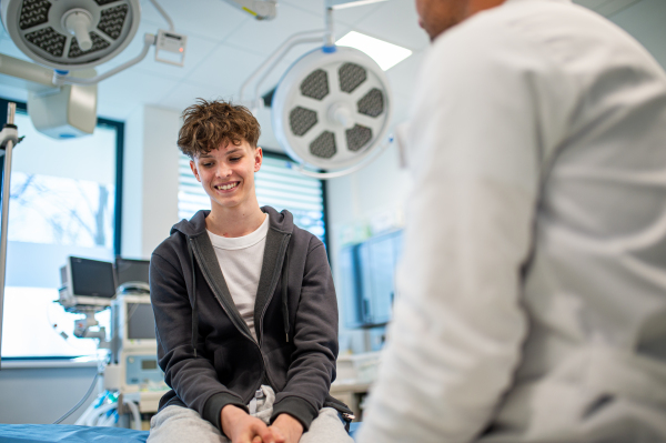 Teenage boy smiling during supportive medical consultation after receiving positive health news.