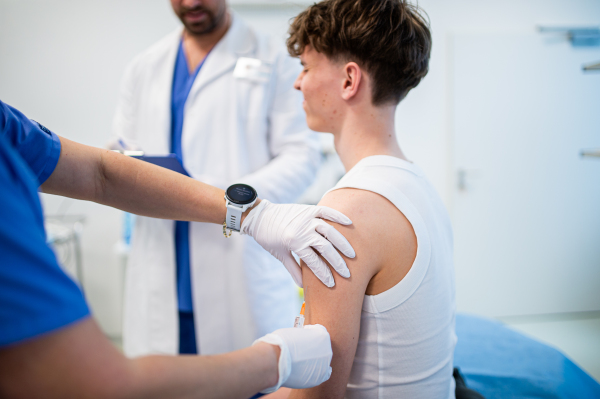 Teenage boy receiving vaccination during routine health checkup at hospital