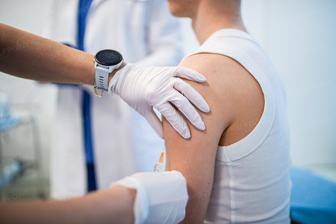 Teenage boy receiving vaccination during routine health checkup in clinic.