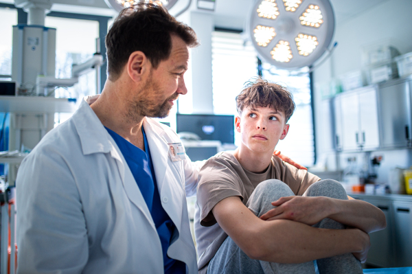 Teenager confiding in doctor about personal and health problems. Mental health evaluation for depressed teen boy.