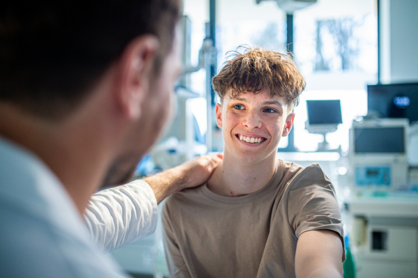Compassionate doctor supporting anxious teenage patient before surgery. Mental health evaluation for depressed teen boy.