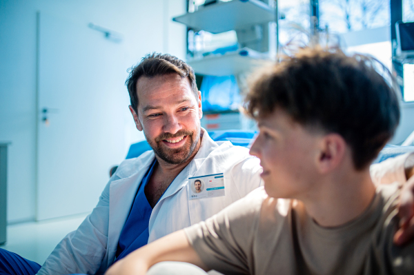 Compassionate doctor supporting anxious teenage patient before surgery. Mental health evaluation for depressed teen boy.