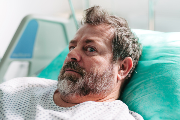 Patient lying in hospital bed, looking at camera.