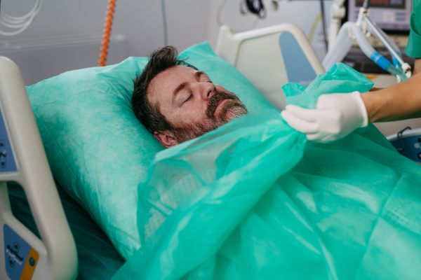 Doctor covering body of unresponsive patient in emergency room.