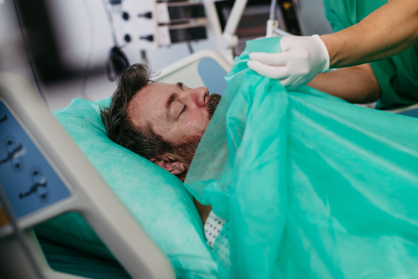 Doctor covering body of unresponsive patient in emergency room.