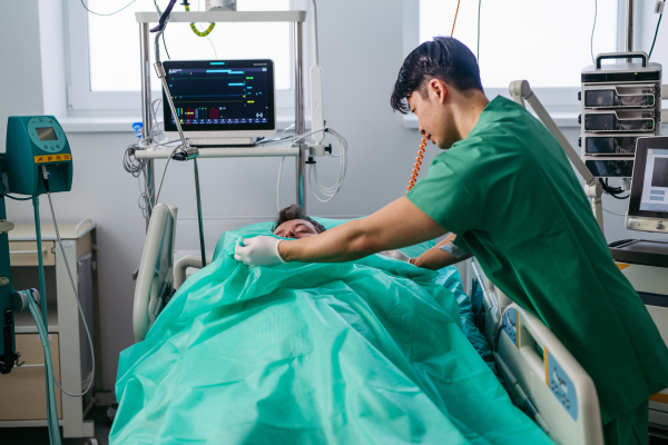 Doctor covering body of unresponsive patient in emergency room.