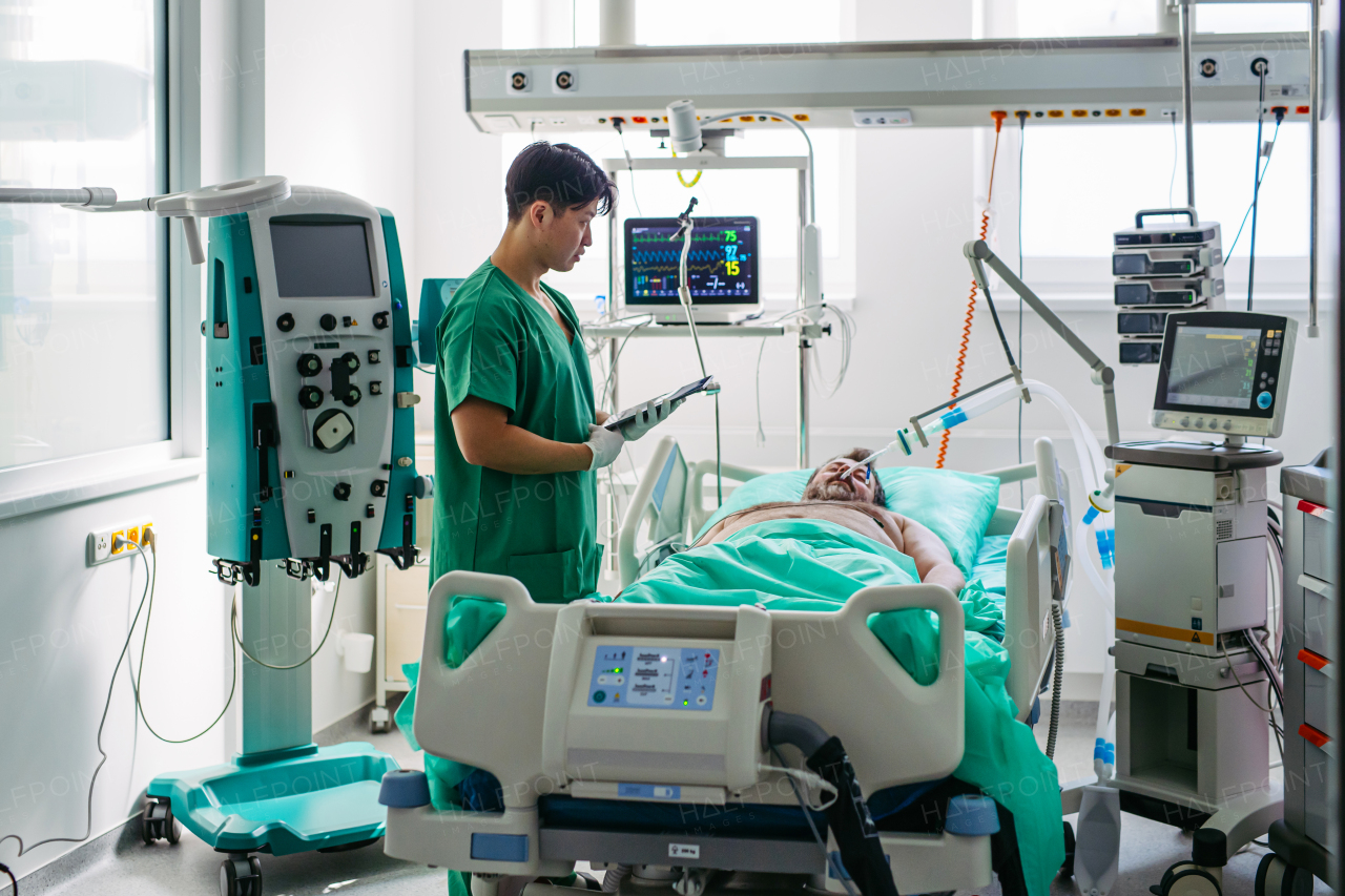 Doctor taking care of unconscious patient in hospital bed. Intensive care unit.