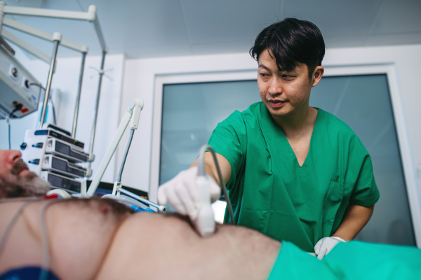 Medical professional using ultrasound probe in intensive care, abdominal ultrasound.