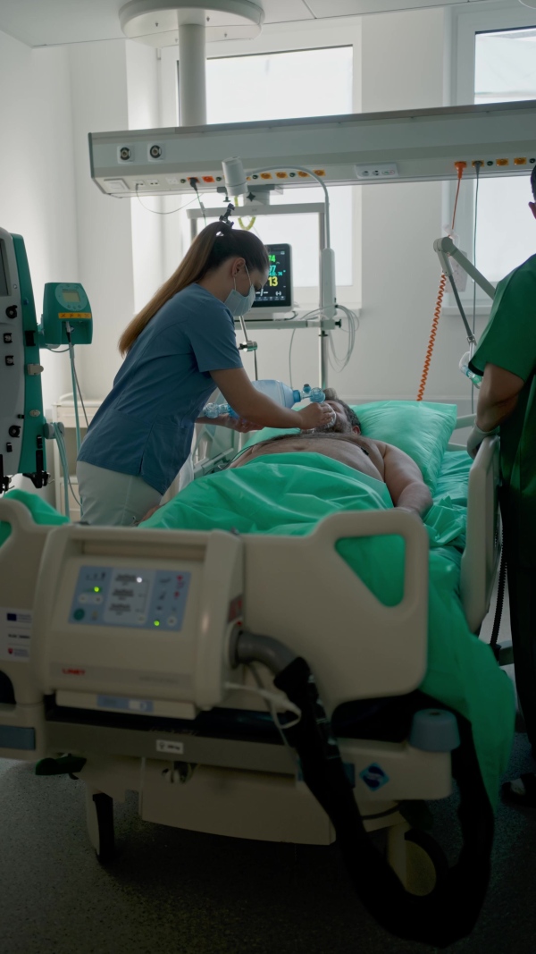 Medical team providing oxygen ventilation to unconscious patient in hospital.
